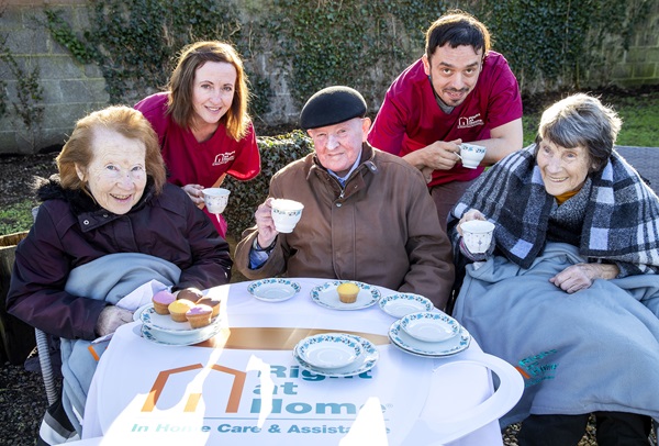 Two Right at Home caregivers having tea with three senior clients outside